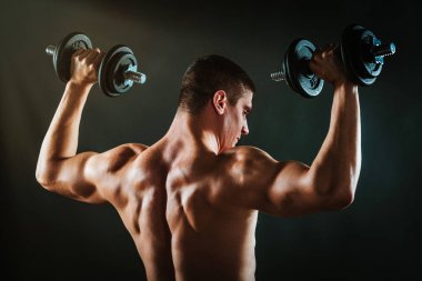 Arkadan görünüş mükemmel kaslı adam egzersiz dumbbells ile
