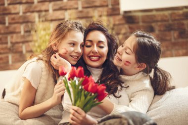 Çiçek tutan ve küçük kız öpücük vererek hayran neşeli anne