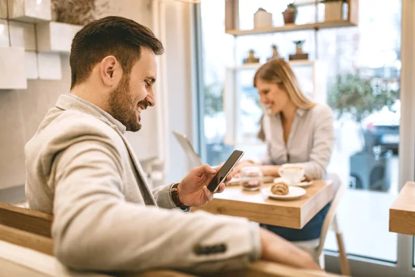 Homem Usando Smartphone Jovem Mulher Sorrindo Trabalhando Laptop Bebendo Café — Fotografia de Stock