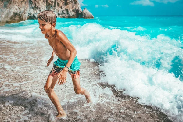 少年はビーチで楽しむ海の波から実行しています — ストック写真