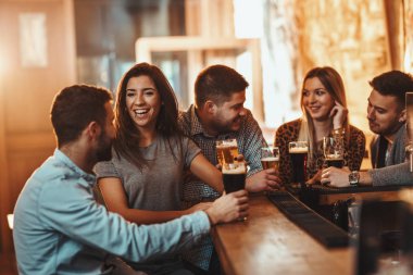 Bira içmek, konuşmak ve having fun kafede arkadaşlar genç grup