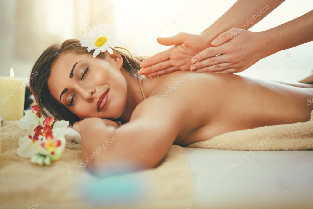 young woman enjoying back massage at spa