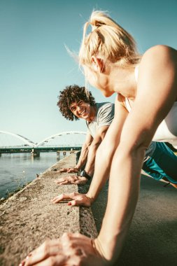 Genç çift gülümseyen eğitim açık havada sırasında açık şınav mutlu eğitim tarafından Nehri.