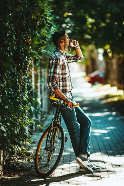 コーヒーを飲むと 自転車の横に立っている中年のスタイリッシュな男性 — ストック写真