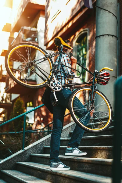 上の階の建物の入り口に自転車を運ぶカジュアルなビジネスマン — ストック写真