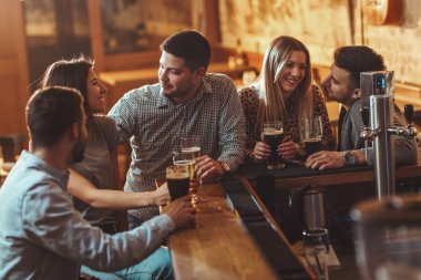 Bira içmek, konuşmak ve having fun kafede arkadaşlar genç grup