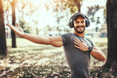 Sonbahar Park germe egzersiz yaparak kulaklık ile genç adam