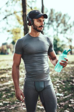 İçme suyu ve eğitim sonbahar Park sonra dinlenme kulaklık ile genç adam