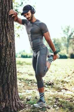 Sonbahar Park germe egzersiz yaparak kulaklık ile genç adam