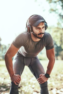 Parkta koşu sonra dinlenme kulaklık ile genç adam