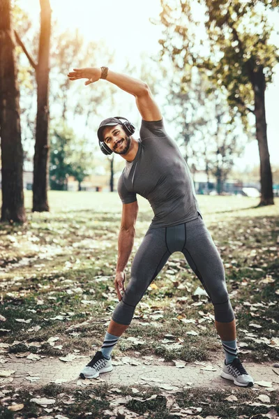 Молодой Человек Наушниках Делает Упражнения Растяжку Осеннем Парке — стоковое фото