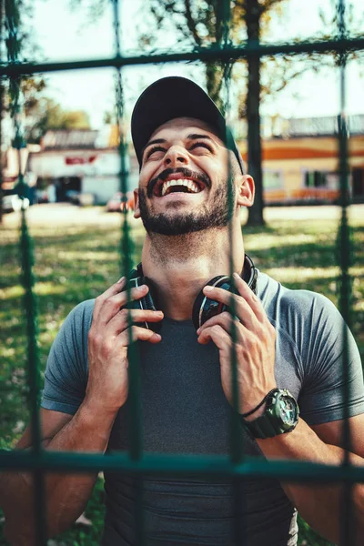 Joven Deportista Sonriente Con Auriculares Descansando Después Entrenar Parque —  Fotos de Stock