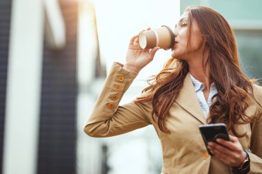genç gülümseyen kadın kahve içme ve akıllı telefon kullanma