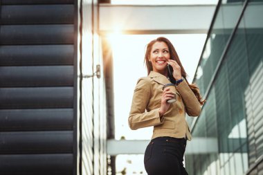 genç gülümseyen kadın kahve içme ve akıllı telefon kullanma