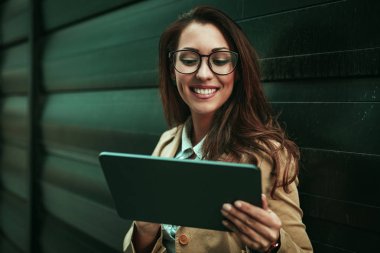 Genç başarılı gülümseyen kadın ofis bölgesinde dijital tablet tutarak