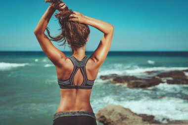 Sahilde sert eğitim sonra rahatlatıcı genç kadının arka görünümü