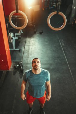 Genç kaslı adam jimnastik salonunda jimnastik yapmaya hazırlanıyor.