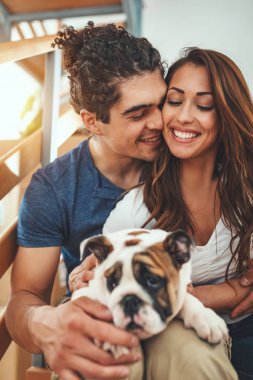 Young couple with little puppy resting after unboxing in new home