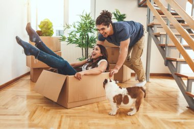 Young couple with little puppy resting after unboxing in new home