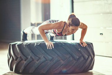 Crossfit eğitim, lastik üzerinde push-up egzersiz yaparak genç kaslı kadın