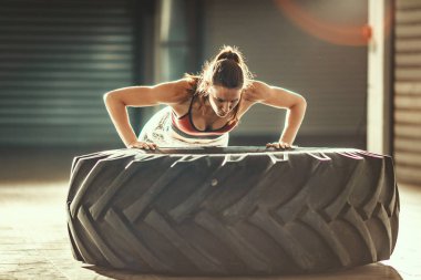 Crossfit eğitim, lastik üzerinde push-up egzersiz yaparak genç kaslı kadın