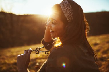 Engebeli arazide sıcak bir akşamın tadını çıkaran gülümseyen genç kadın  