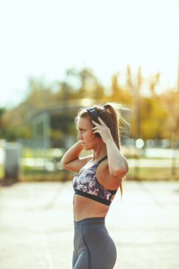 Genç bayan koşucu koşudan önce kulaklıkları takıyor.