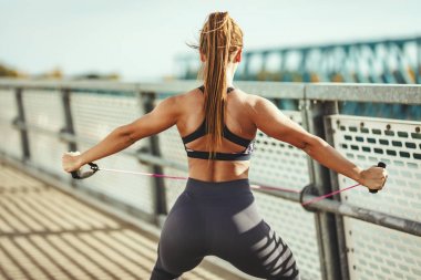 Elastik lastik bant Köprüsü'nde güçlü fit vücut eğitim yaparken kas genç kadın