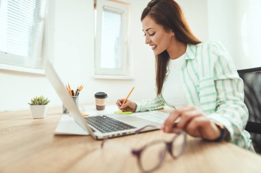 Ofiste çalışan genç gülümseyen başarılı iş kadını