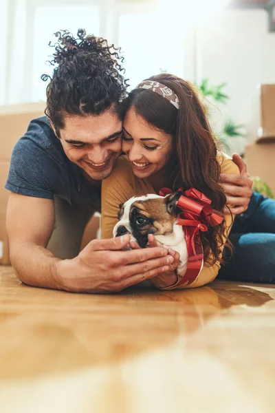 Young Happy Couple Lying Floor Hugging Little Puppy New Home — Stock fotografie