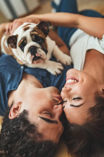 Young Happy Couple Lying Floor Hugging Little Puppy New Home — Stock fotografie