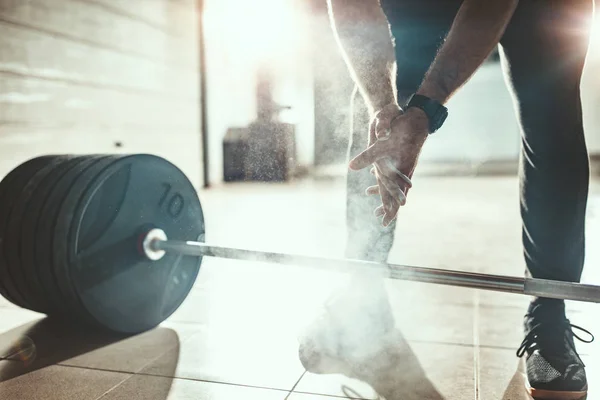 Close view of strong man hand with talc getting ready to weightlifting at garage gym