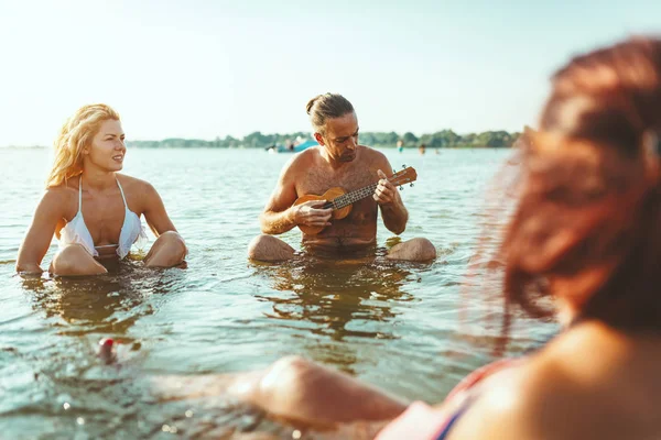 Amigos Sentados Agua Hombre Jugando Ukelele Sol —  Fotos de Stock