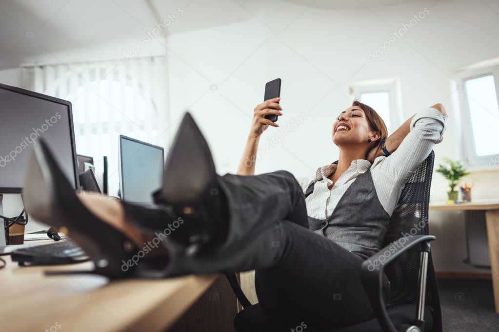 Young successful entrepreneur using smartphone in office