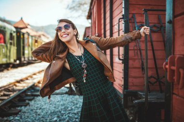 retro tren yanında duran gülümseyen genç kadın