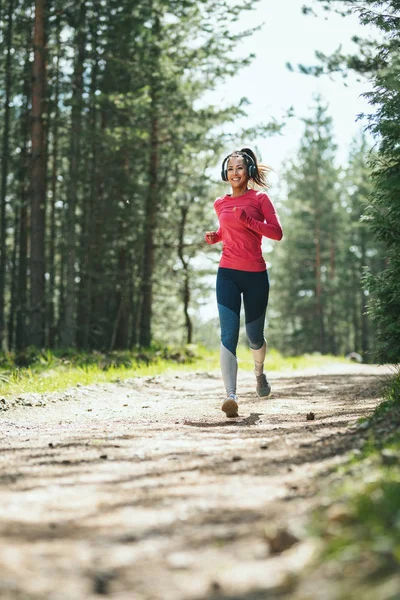 Junge Sportliche Frau Hört Musik Beim Joggen Auf Sonnigem Waldweg — Stockfoto