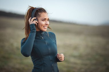 Genç gülen koşucu müzik dinliyor ve dağlarda koşuya hazırlanıyor.