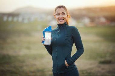 Genç bayan su içiyor ve dağlarda koşuya hazırlanıyor.