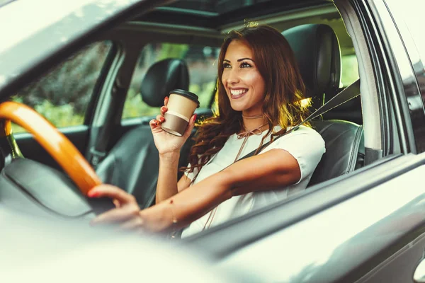 年轻的微笑的女人拿着一杯咖啡和驾驶汽车 — 图库照片
