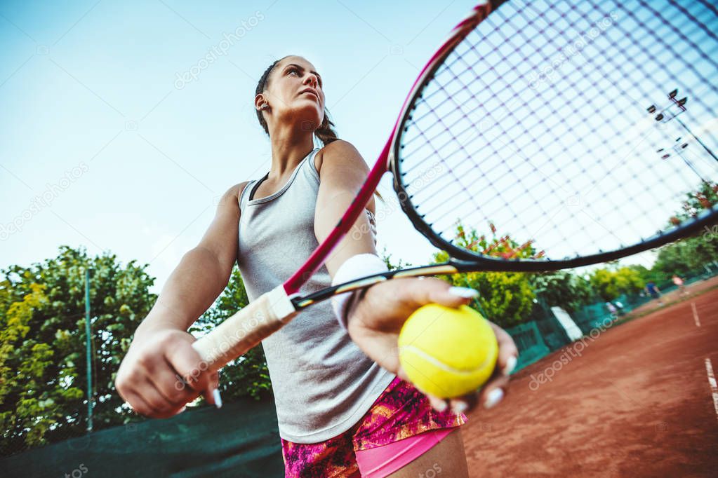 Young female tennis player preparing to serve on tennis match