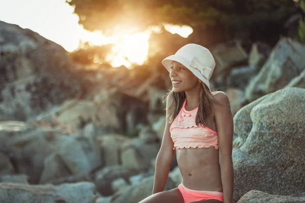 日没時に岩のビーチでリラックス幸せなティーンエイジャーの女の子 — ストック写真