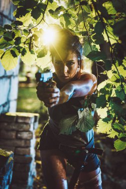 Young female special forces holding gun and getting ready for attack in abandoned ruins clipart