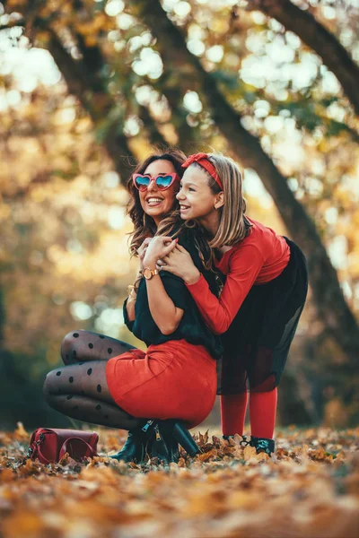 年轻时尚的母亲与女儿走在温暖的秋天森林在日落 — 图库照片