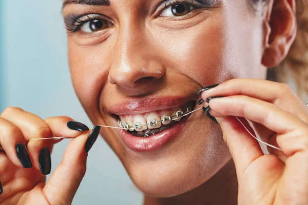 Zbliżenie Uśmiechniętej Kobiety Twarz Szelkami Zęby Flossing — Zdjęcie stockowe