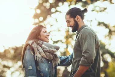 Genç çift sonbahar güneşli parkta yürüyüş