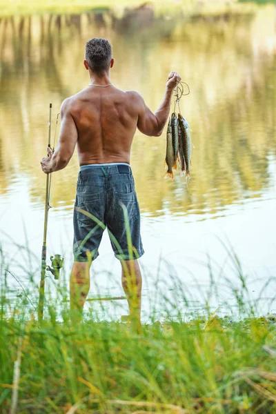 Vista Trasera Joven Pescador Guapo Satisfecho Está Sosteniendo Los Peces — Foto de Stock