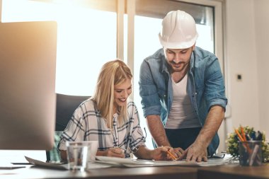 Yeni bir proje üzerinde çalışan iki genç mimar ofis planlarını analiz ediyor.