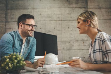 Yeni bir proje üzerinde çalışan iki genç mimar ofis planlarını analiz ediyor.