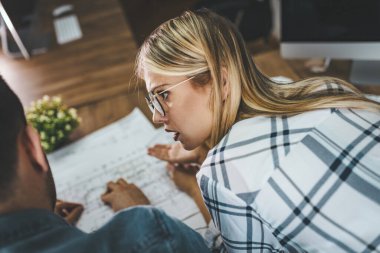 Yeni bir proje üzerinde çalışan iki genç mimar ofis planlarını analiz ediyor.