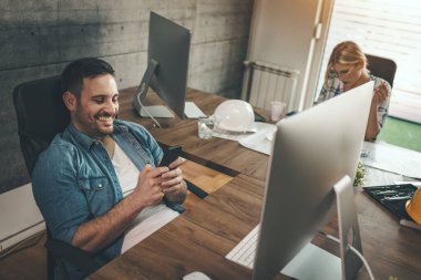 İki genç mühendis meslektaşı ofiste yeni bir proje üzerinde çalışıyor.